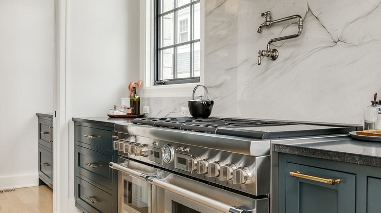 A luxury kitchen with stone countertops, a large range cooker, and a pot-filler faucet on the wall above the stove