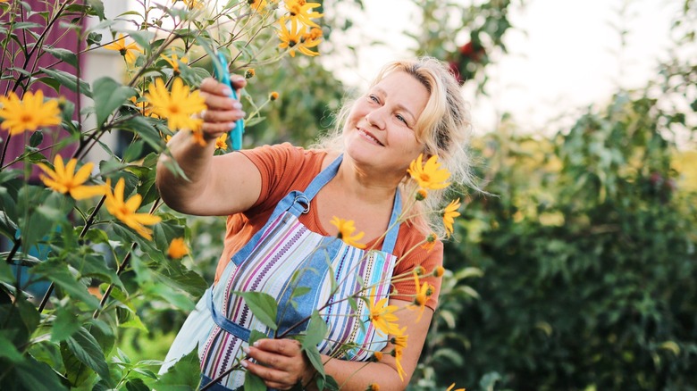 A woman happily pruning flowers