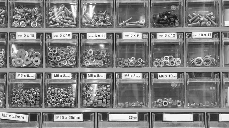 Various metal hardware pieces organized into clear storage bins with labels