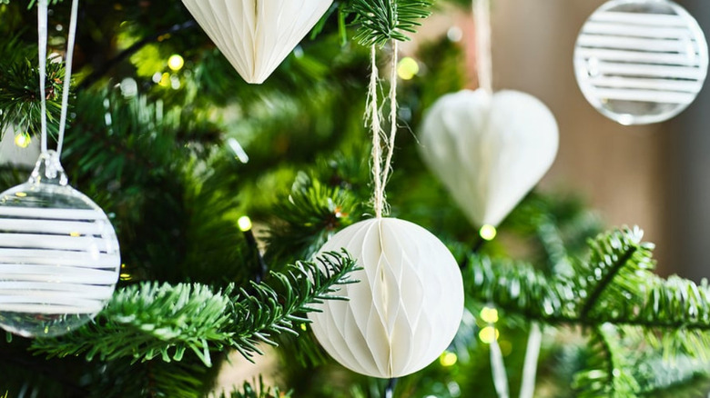 Mixed shapes white paper ornaments hanging from the tree alongside round clear ornaments