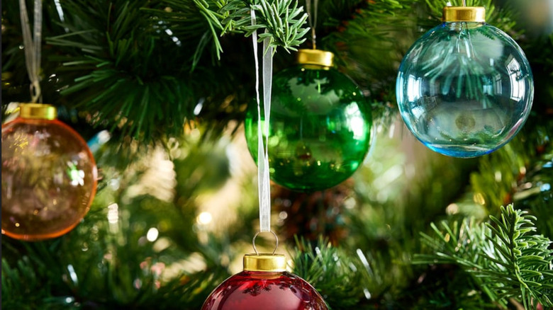 Glass and see-through round Christmas tree ornaments on the tree reflecting the light