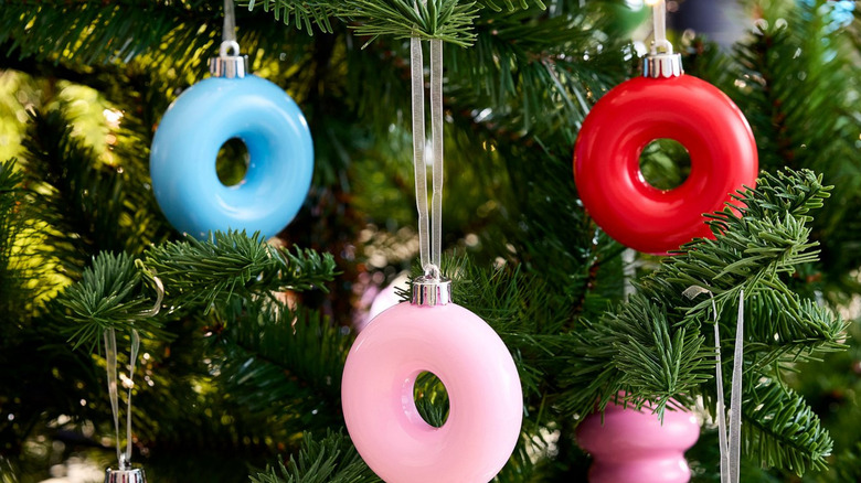 Three donut-shaped ornaments in pink, blue, and red hanging from a tree