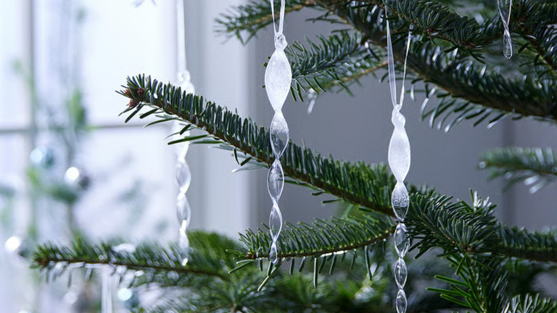 Glass icicle ornaments hanging from a Christmas tree in front of a window
