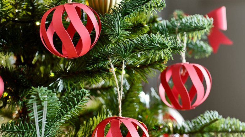 Hollow red paper ornaments hanging on a Christmas tree with other onraments in the background