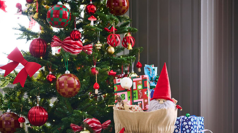 A cropped image of a Christmas tree with the focus on the ornaments in the center of the tree and a few presents