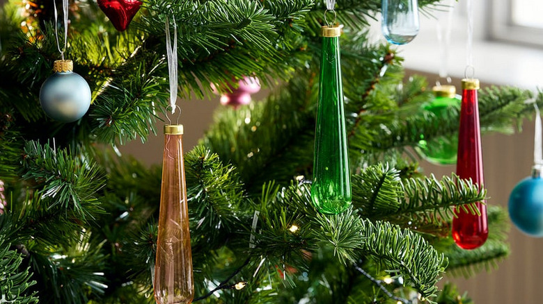 Colorful teardrop ornaments hanging from a Christmas tree with other small baubles around them