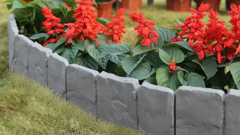 Cobblestone garden border surrounding a red flower garden