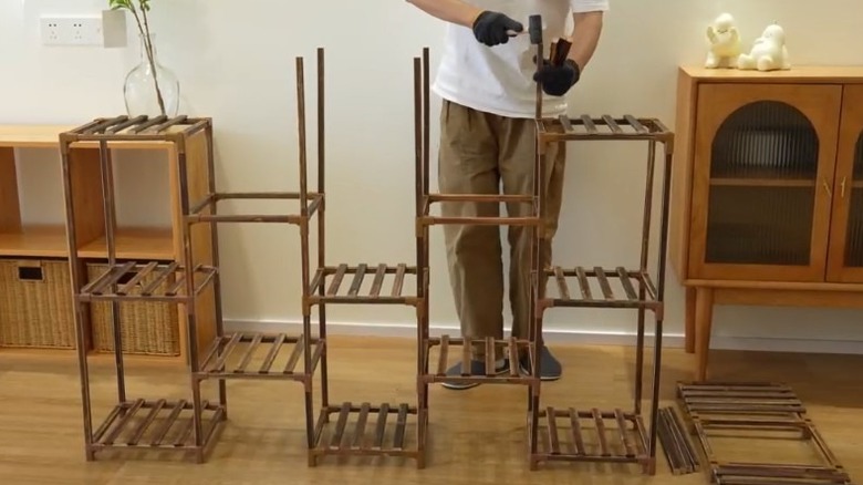 Photograph of a man building the plant stand in a home environment