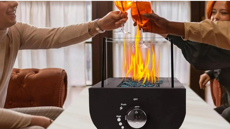 individuals toasting drinks with a fire pit in the center of the table