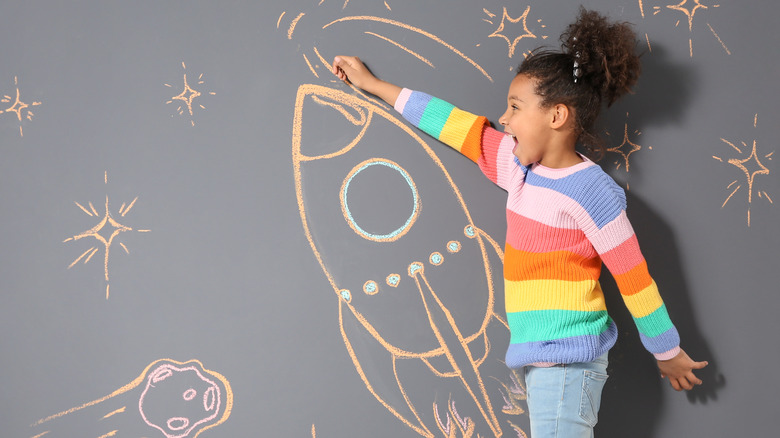 Child drawing on chalkboard wall