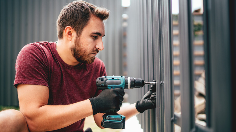 Man drilling metal fence