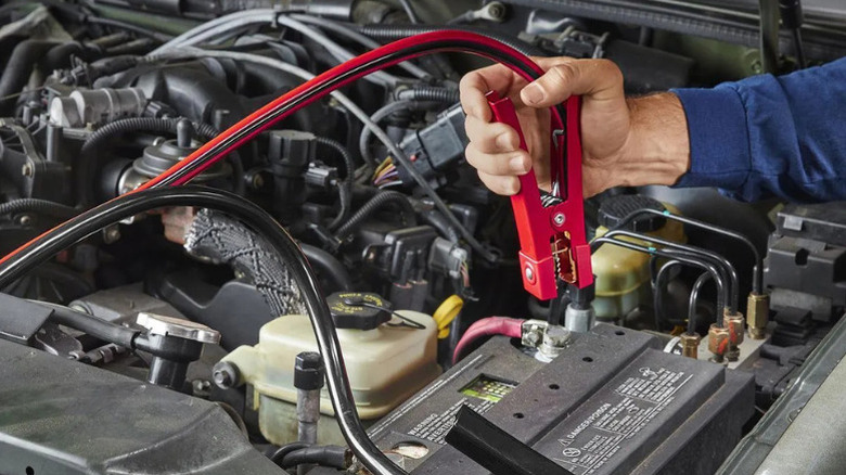 Close-up of a hand using Viking jump cables to start a car