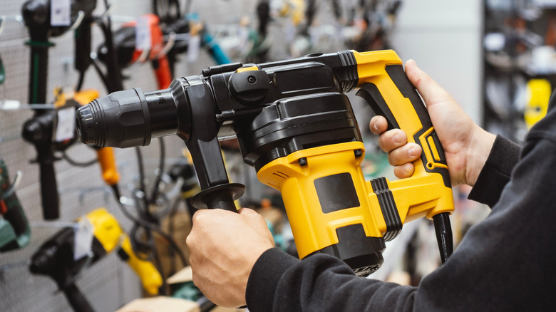 Close up of a person holding a heavy-duty power tool in a store