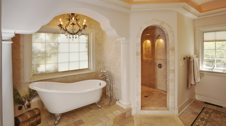 A clawfoot tub with a chandelier over it in a unique bathroom