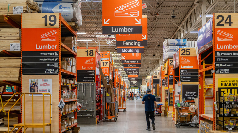 A shopper walking through a Home Depot aisle filled with different products