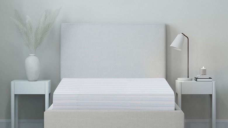 A thick memory foam mattress sits in a neutral bedroom