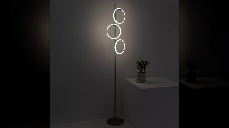 A Brightech Saturn Removable Light Rings Floor Lamp is shown illuminating a dark room