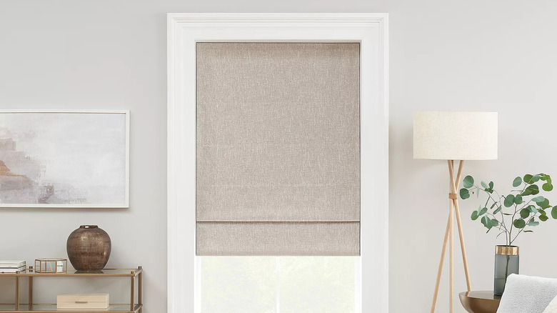 A beige linen cordless Roman shade covers a window in a neutral living room