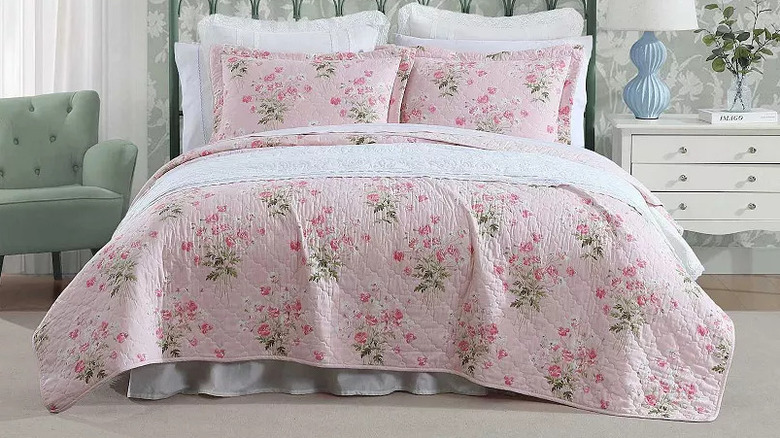 A large bed is covered with a pink floral Laura Ashley Quilt Set