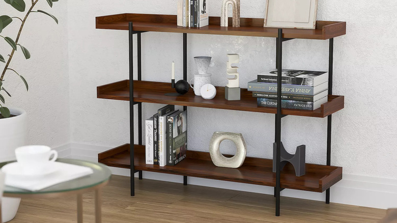 A rustic wood and black metal shelving unit holds books and decorative items