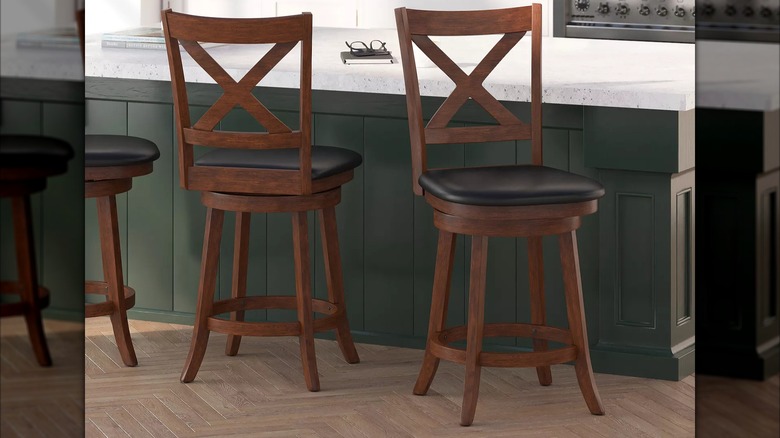 Two padded swivel bar chairs sit in front of a white kitchen island countertop