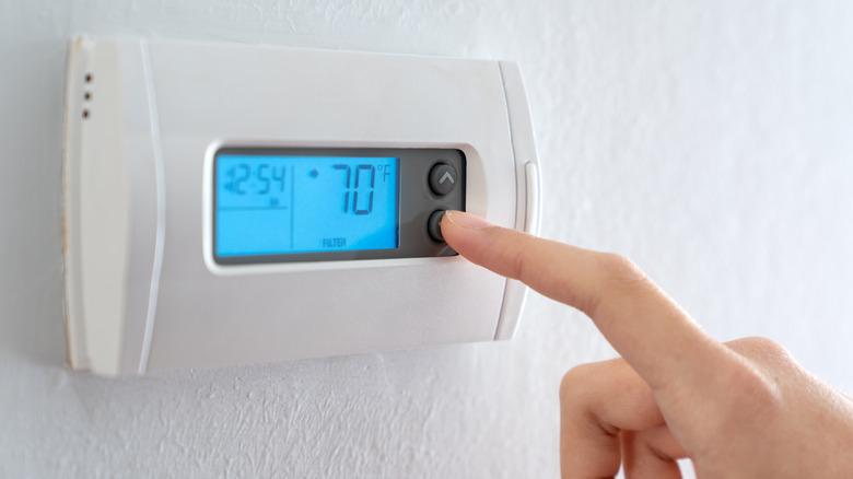 Closeup of a person's hand adjusting a thermostat