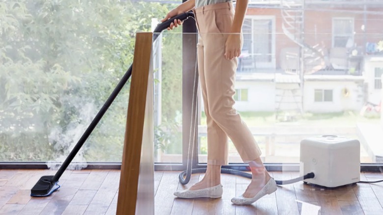 Woman steam cleaning her wood floors.