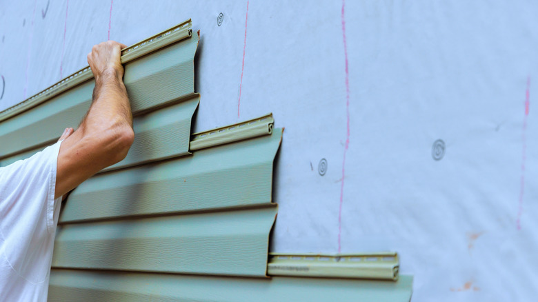 A worker carefully fitting vinyl siding panels
