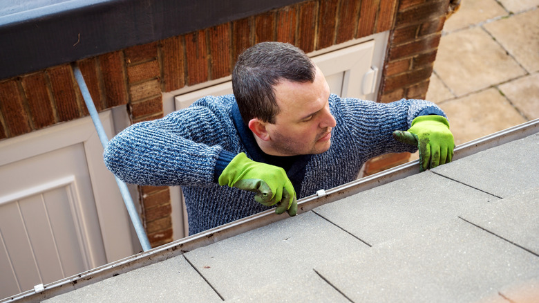 A man working on a house's roofline at the top of a ladder