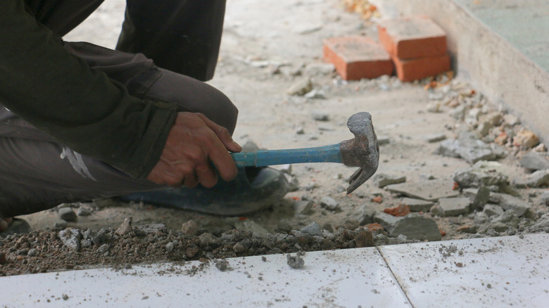 Hand using hammer to break up a concrete floor