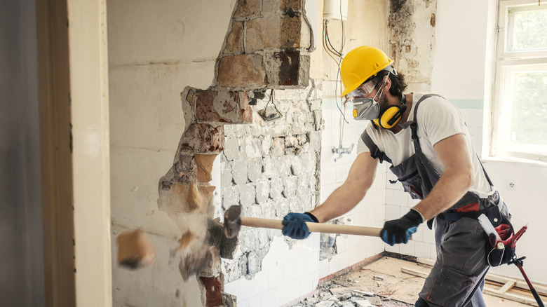 Man using a hammer to tear down a wall