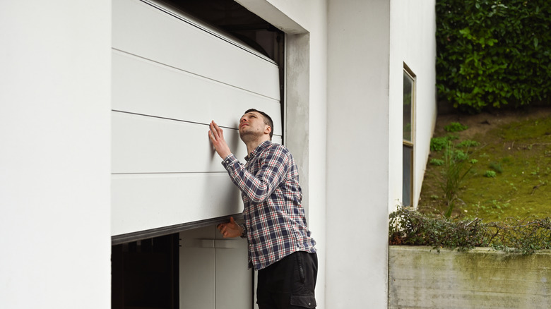 Man looking at a white, half-closed garage door