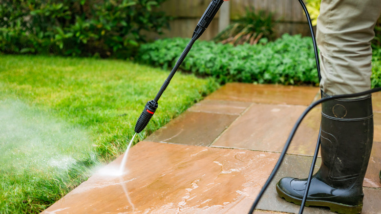 Person in boots pressure washing their patio