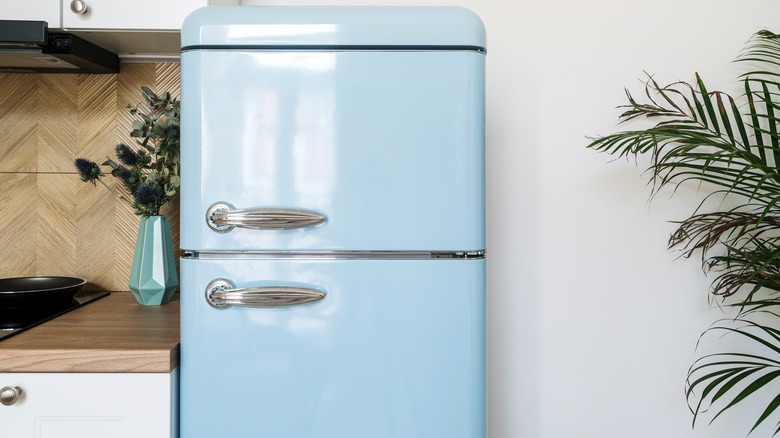 Light blue retro fridge next to a teal vase
