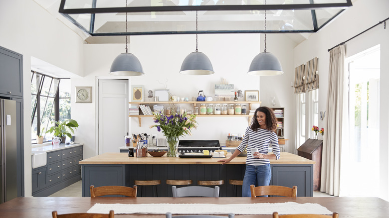Smiling woman standing in kitchen with blue light fixtures
