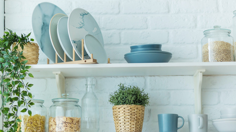 Blue dishes sitting on open shelves against a brick wall