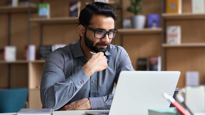 man pensively looking at laptop