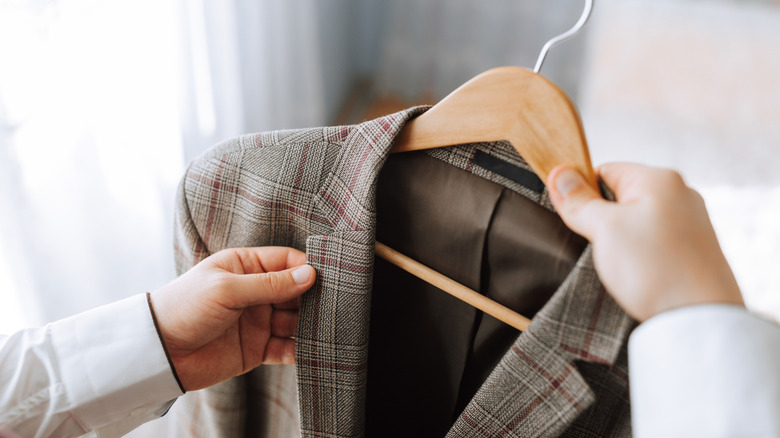 A person holding a plaid jacket on a hanger