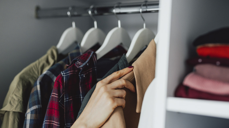 Zoomed in image of coat closet with a woman's hand grabbing a jacket
