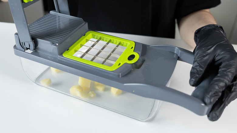 Gloved hands holding a manual vegetable slicer