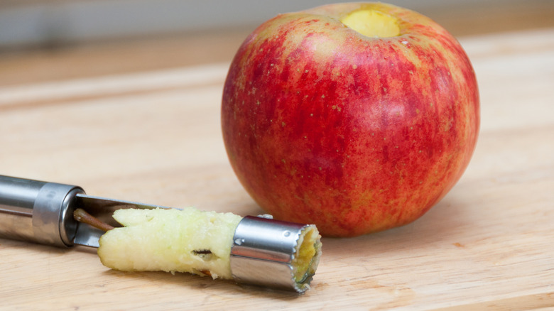 Apple corer next to a cored out apple