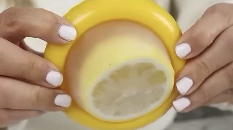 Painted hands holding a lemon storage container