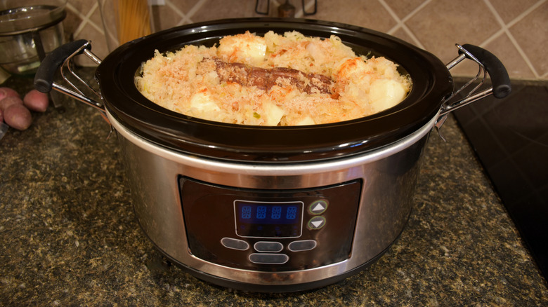 A slow cooker with a cooked dish inside on a counter