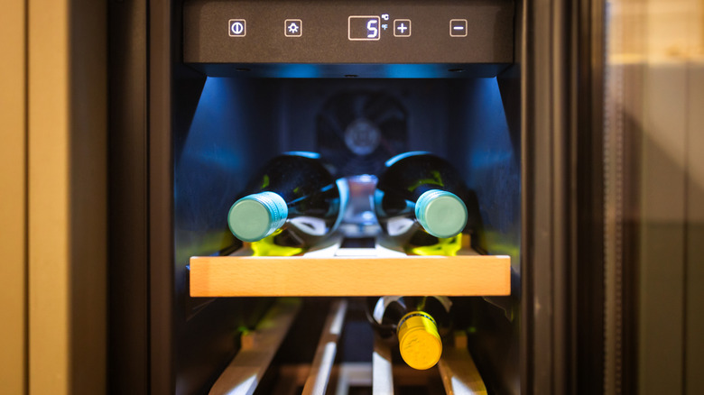 A wine fridge with three bottles of wine in it