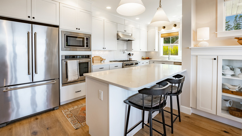 A white kitchen with a large stainless steel fridge.