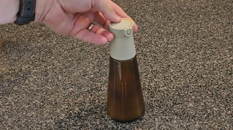 Someone testing an IKEA sauce bottle on a stonelike countertop