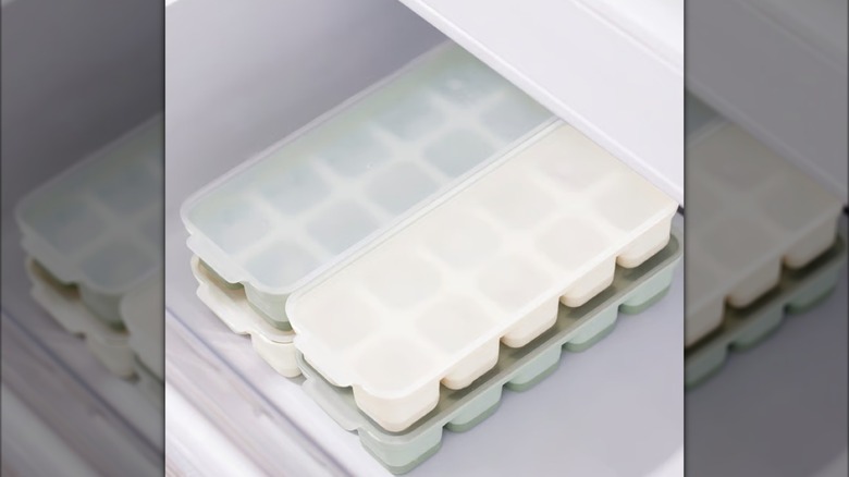 Stacked pastel IKEA ice trays stacked inside a freezer drawer