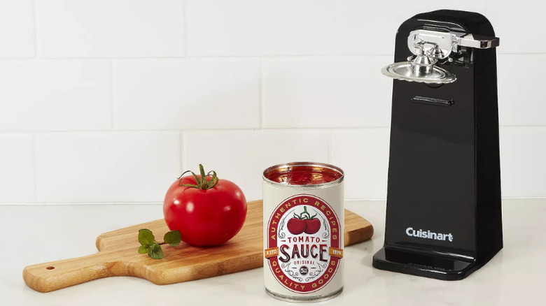 Cuisinart's Deluxe Can Opener, black, on a kitchen counter next to an open can of tomato sauce