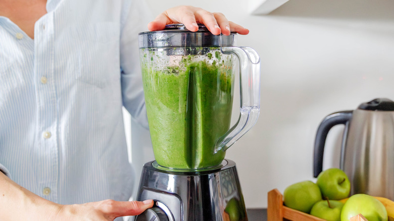 A blender with a green smoothie being made inside
