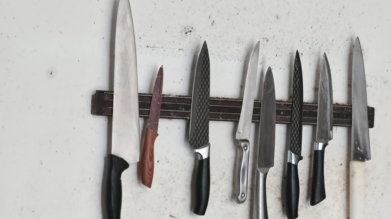 Kitchen knives of various sizes on magnetic wall mount.